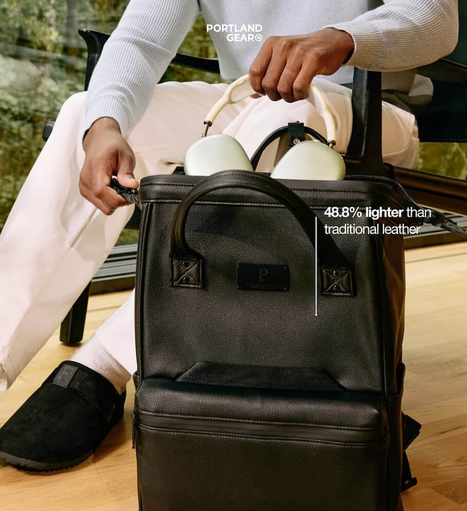 Portland Gear Cascade Backpack in LeatherLite vegan leather being packed by a man sitting in a chair.